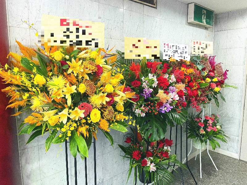 雑居ビルのキャバクラ店入り口前に並んだスタンド花の画像