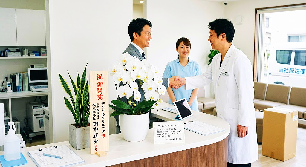清潔で現代的な歯科医院のエントランスで、お祝いの白い大輪胡蝶蘭を挟んで笑顔で握手をする、贈り主の法人代表と白衣姿の院長。